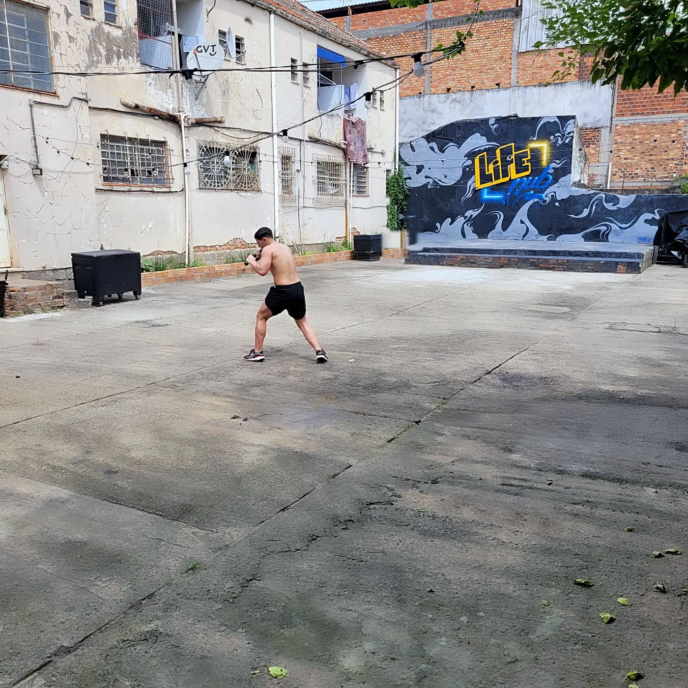 Área externa aberta da PowerLife 4D com pessoa treinando e mural grafitado ao fundo